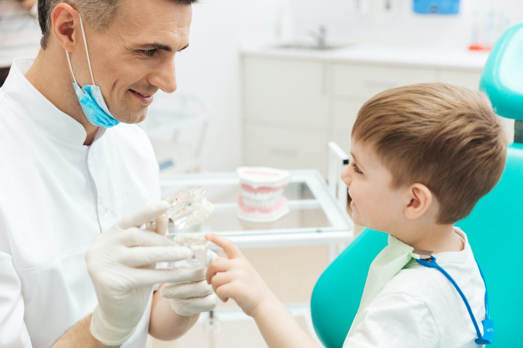 Boy on cosultation of pediatrician dentist using dental jaw model
