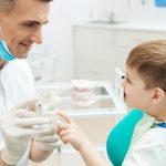 Boy on cosultation of pediatrician dentist using dental jaw model