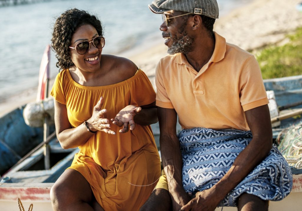 Black couple taling cheerful at the beach together