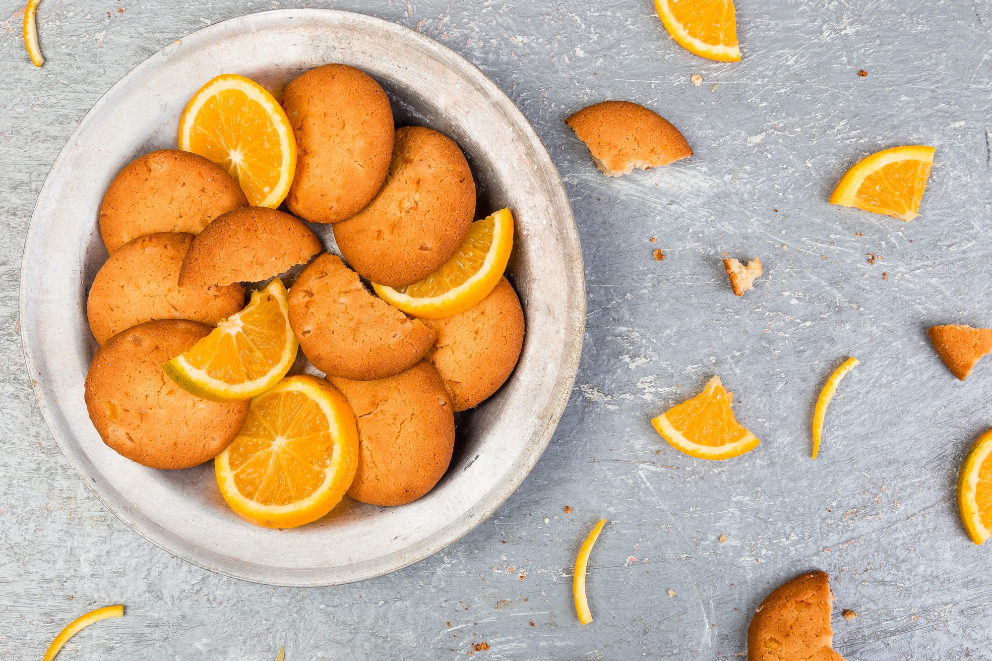 Cookies and orange citrus fruit on metal plate on grey background. Flat lay