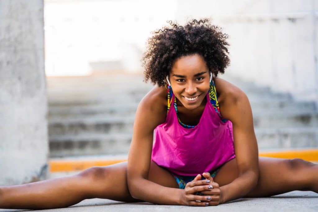 Afro athlete woman stretching legs before exercise.
