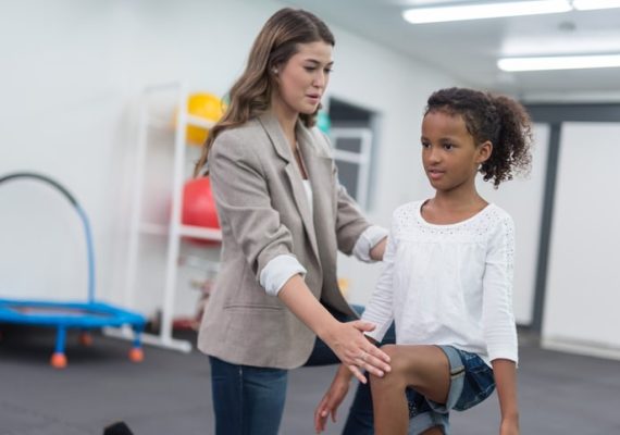 Therapist doing stretching exercise with young African American girl
